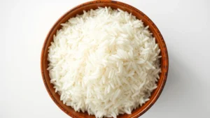 Professional overhead shot of fluffy white basmati rice grains in a ceramic bowl with steam rising, natural kitchen lighting, shallow depth of field, clean white background