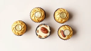 Flat lay of individual Ferrero Rocher chocolates unwrapped showing golden wafer layers, hazelnut center, and milk chocolate coating on neutral background with natural lighting, emphasizing texture and layers