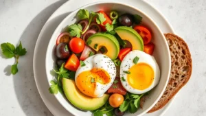 Overhead shot of vibrant breakfast bowl with fresh vegetables, poached eggs, avocado slices, and whole grain toast on white ceramic plate, natural morning light, no text or labels visible