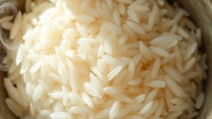 Close-up overhead view of cooked jasmine rice grains in a ceramic bowl with steam rising, natural daylight illumination, shallow depth of field focusing on individual rice grain texture and translucent appearance, minimalist composition